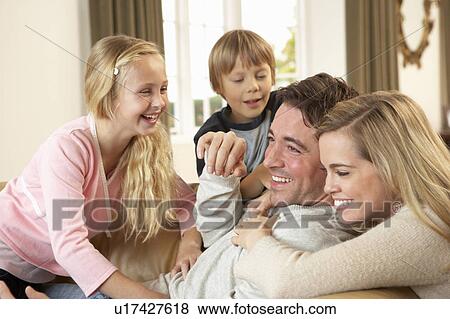 Happy young family playing together on sofa View Large Photo Image Stock Photo - Happy young family playing together on sofa. Fotosearch
