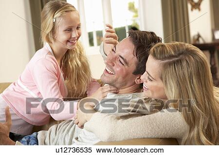 Stock Photography - Happy young family playing together on sofa. Fotosearch