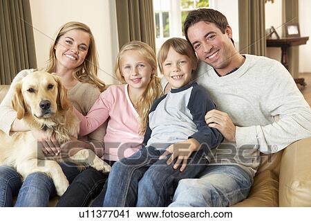 Happy young family sitting on sofa holding a dog View Large Photo Image Stock Image - Happy young family sitting on sofa holding a dog. Fotosearch