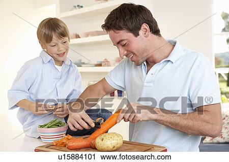 Happy young man with boy peeling vegetables in kitchen View Large Photo Image Stock Image - Happy young man with boy peeling vegetables in kitchen. Fotosearch