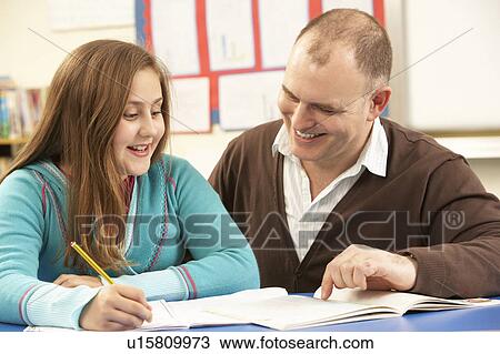 Stock Image - Male Pupil Studying in classroom with teacher. Fotosearch