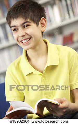 Picture - Male Teenage Student In Library Reading Book. Fotosearch