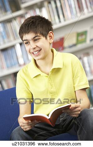 Stock Photograph - Male Teenage Student In Library Reading Book. Fotosearch