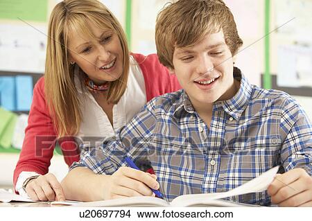 Picture - Male Teenage Student Studying In Classroom With Teacher. Fotosearch