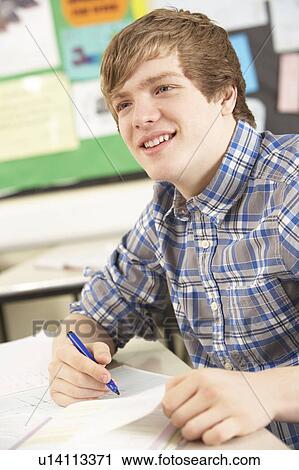 Stock Image - Male Teenage Student Studying In Classroom. Fotosearch