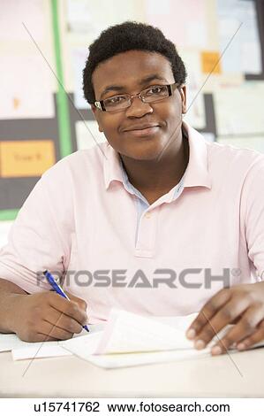 Stock Image - Male Teenage Student Studying In Classroom. Fotosearch