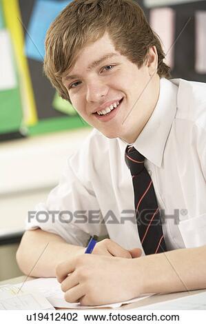 Stock Image - Male Teenage Student Studying In Classroom. Fotosearch