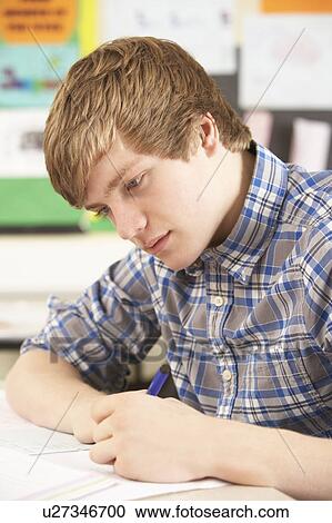 Stock Image - Male Teenage Student Studying In Classroom. Fotosearch