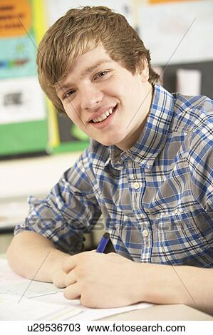 Stock Image - Male Teenage Student Studying In Classroom. Fotosearch