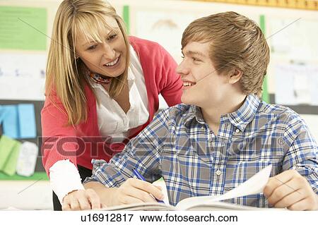 Stock Photo - Male Teenage Student Studying In Classroom With Teacher. Fotosearch