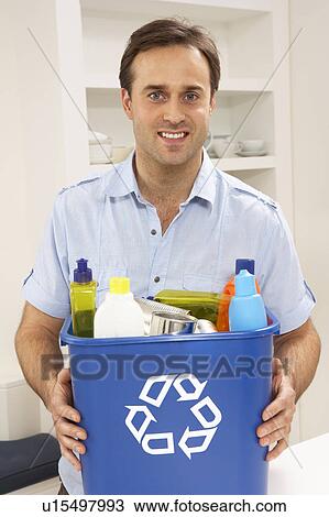 Stock Image - Man Holding Recyling Waste Bin At Home. Fotosearch