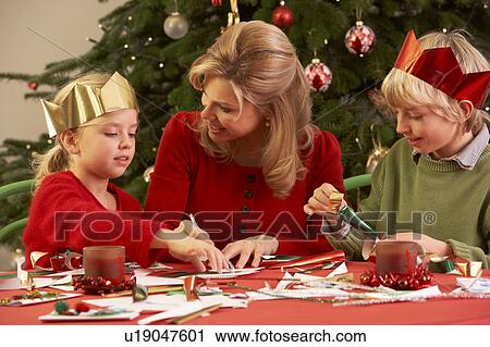 Stock Image - Mother And Children Making Christmas Cards Together. Fotosearch