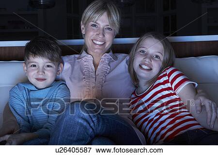 Mother And Children Watching Programme On TV Sitting On Sofa Together View Large Photo Image Stock Photo - Mother And Children Watching Programme On TV Sitting On Sofa Together. Fotosearch