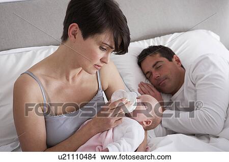 Picture - Mother Feeding Newborn Baby In Bed At Home. Fotosearch