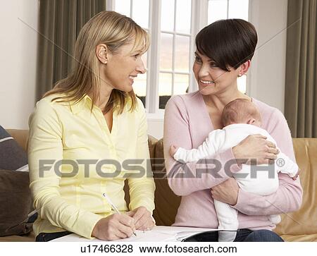 Stock Photo - Mother With Newborn Baby Talking With Health Visitor At Home. Fotosearch