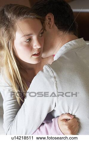 Stock Image - Nervous Looking Teenage Girl Sitting On Sofa At Home With Boyfri. Fotosearch