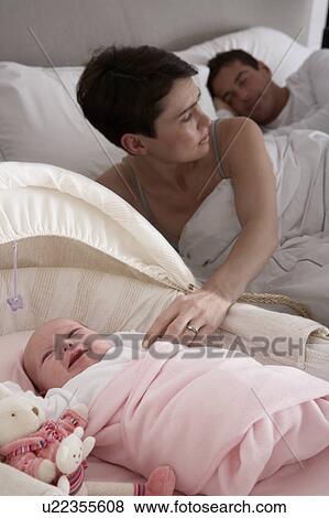 Stock Photo - Newborn Baby Crying In Cot In Parents Bedroom. Fotosearch
