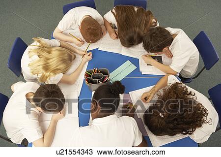 Stock Image - Overhead View Of Schoolchildren Working Together At Desk. Fotosearch