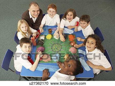 Stock Image - Overhead View Of Schoolchildren Working Together At Desk. Fotosearch