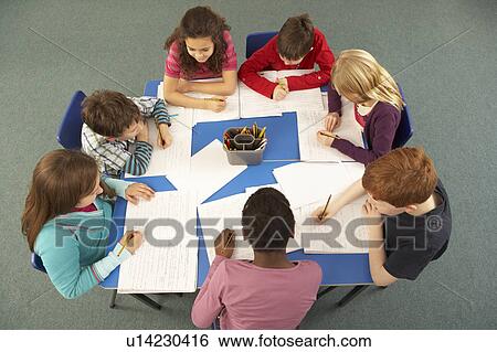Stock Photograph - Overhead View Of Schoolchildren Working Together At Desk. Fotosearch