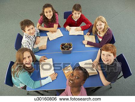 Stock Photograph - Overhead View Of Schoolchildren Working Together At Desk. Fotosearch