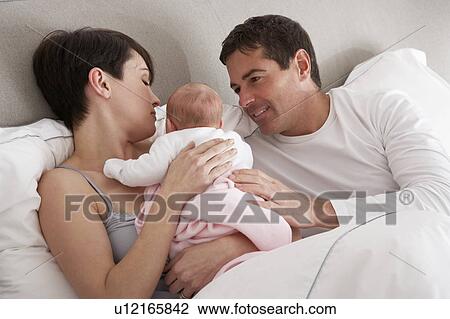Parents Cuddling Newborn Baby In Bed At Home View Large Photo Image Stock Image - Parents Cuddling Newborn Baby In Bed At Home. Fotosearch