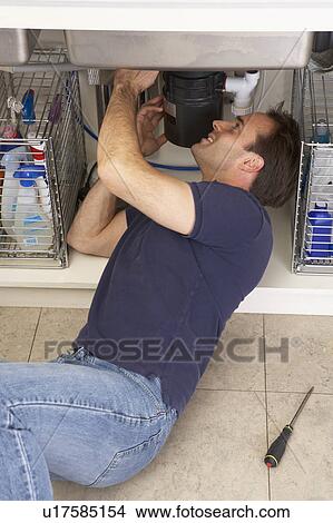 Picture - Plumber Working On Sink In Kitchen. Fotosearch