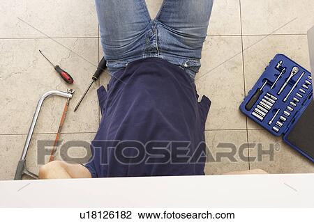 Stock Image - Plumber Working On Sink In Kitchen. Fotosearch