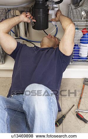 Stock Photo - Plumber Working On Sink In Kitchen. Fotosearch