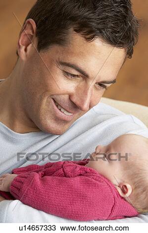 Stock Image - Portrait Of Father With Newborn Baby At Home. Fotosearch