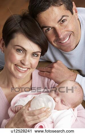 Stock Image - Portrait Of Parents Feeding Newborn Baby At Home. Fotosearch
