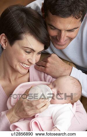 Stock Image - Portrait Of Parents Feeding Newborn Baby At Home. Fotosearch