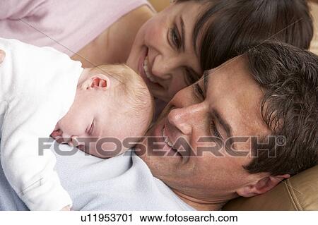 Stock Image - Portrait Of Proud Parents With Newborn Baby At Home. Fotosearch