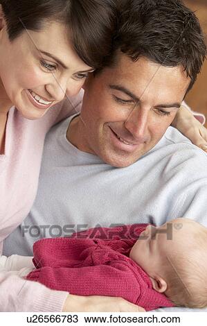 Stock Image - Portrait Of Proud Parents With Newborn Baby At Home. Fotosearch