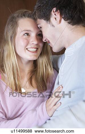 Stock Photo - Romantic Teenage Couple Sitting On Sofa At Home Together. Fotosearch