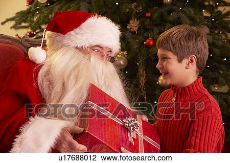 Santa Claus Giving Gift To Boy In Front Of Christmas Tree View Large Photo Image Stock Image - Santa Claus Giving Gift To Boy In Front Of Christmas Tree. Fotosearch