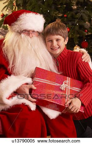 Santa Claus Giving Gift To Boy In Front Of Christmas Tree View Large Photo Image Stock Photography - Santa Claus Giving Gift To Boy In Front Of Christmas Tree. Fotosearch