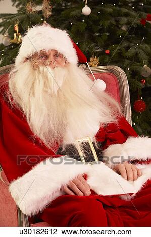 Santa Claus Sitting In Armchair In Front Of Christmas Tree View Large Photo Image Stock Image - Santa Claus Sitting In Armchair In Front Of Christmas Tree. Fotosearch