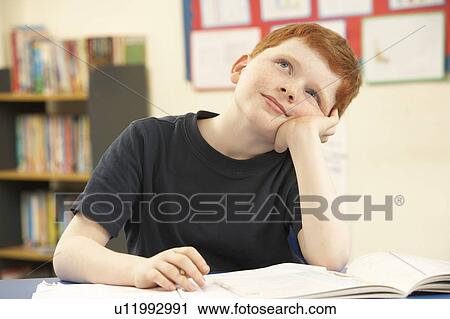 Stock Image - Schoolboy Daydreaming In Classroom. Fotosearch