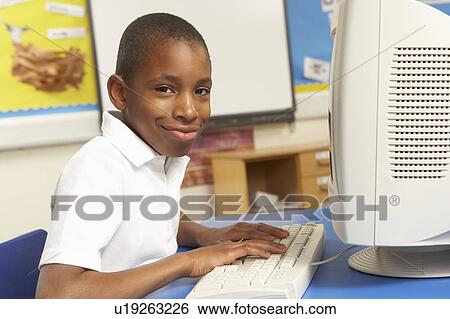 Stock Photograph - Schoolboy In IT Class Using Computer. Fotosearch