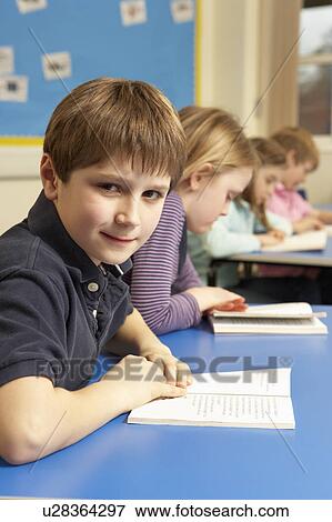 Stock Photo - Schoolboy Reading Book In Classroom. Fotosearch