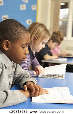 Stock Photograph - Schoolboy Reading Book In Classroom. Fotosearch