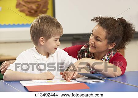 Picture - Schoolboy Studying In Classroom With Teacher. Fotosearch