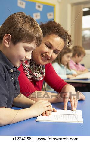 Stock Image - Schoolboy Studying In Classroom With Teacher. Fotosearch