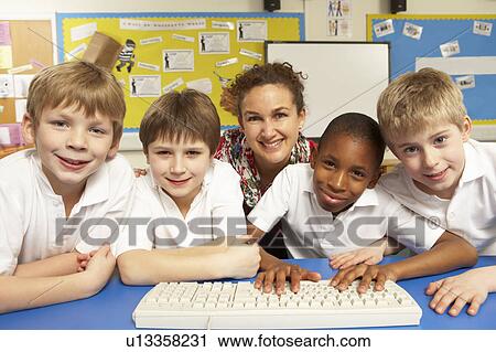 Stock Image - Schoolchildren in IT Class Using Computers with teacher. Fotosearch