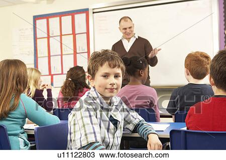 Stock Image - Schoolchildren Studying In Classroom With Teacher. Fotosearch
