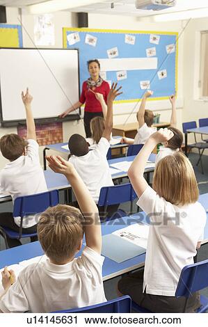 Stock Image - Schoolchildren Studying In Classroom With Teacher. Fotosearch