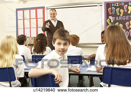Stock Image - Schoolchildren Studying In Classroom With Teacher. Fotosearch