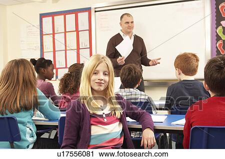 Stock Image - Schoolchildren Studying In Classroom With Teacher. Fotosearch