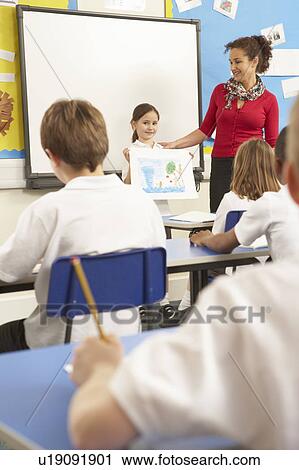 Stock Image - Schoolchildren Studying In Classroom With Teacher. Fotosearch